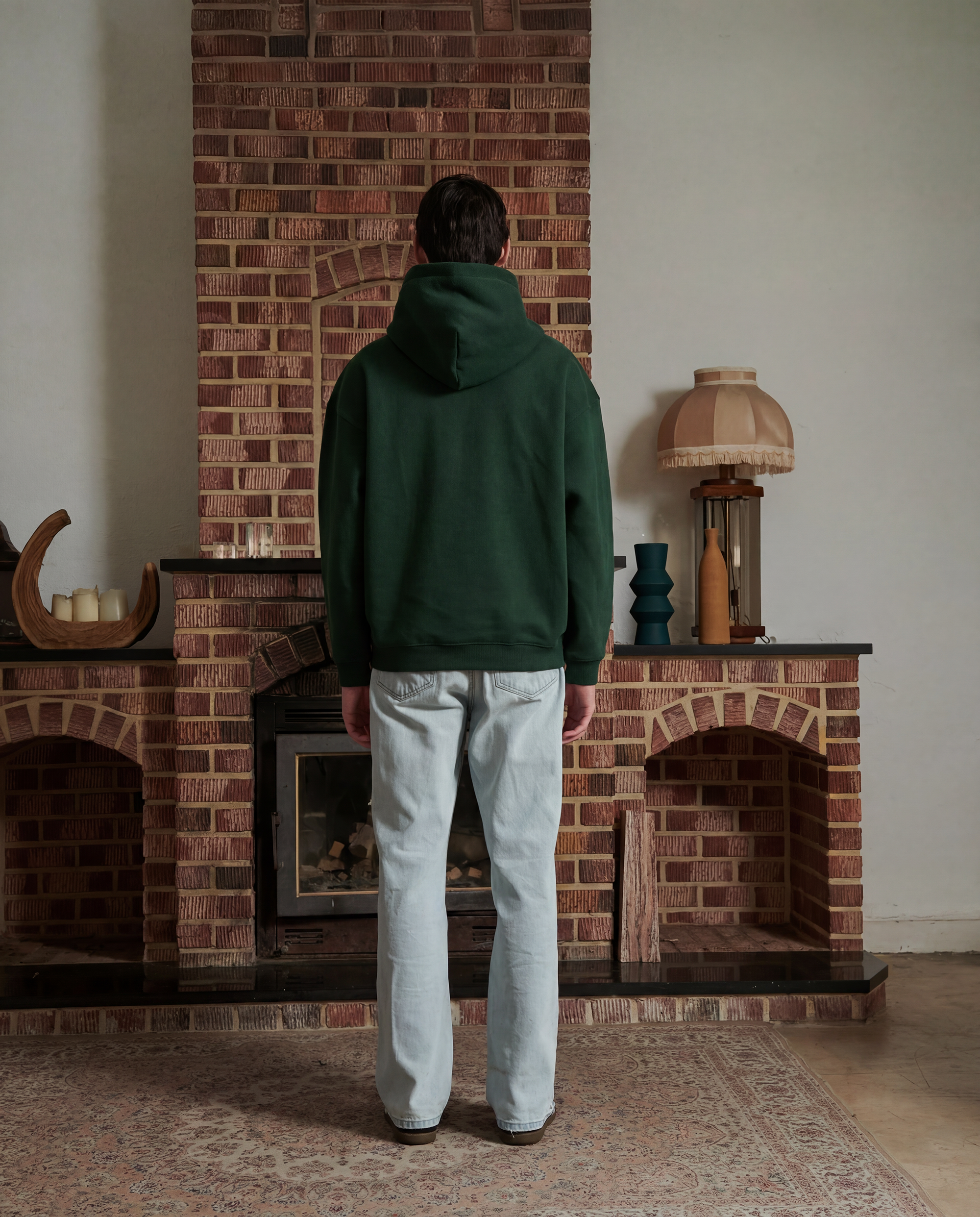 Male model wearing a forest green hoodie facing backward